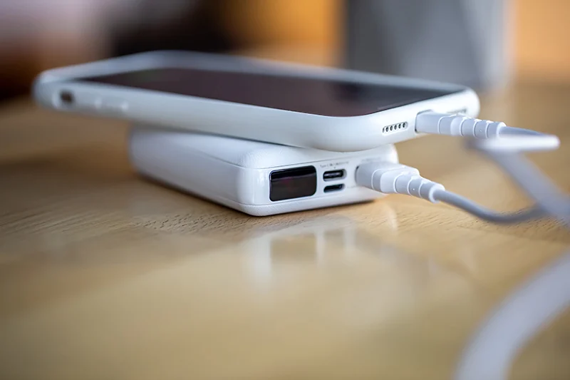 Cellphone connected to a multi-purpose portable charger. Showing the convenience of being able to power a cellphone anywhere