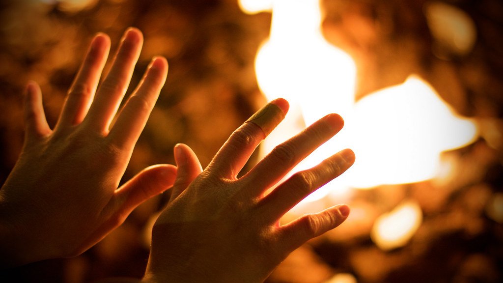 Hands warming over an open fire demonstrating a need for warm hands during the winter